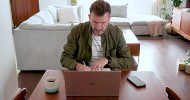 Yılbaşı ağacının yanında dizüstü bilgisayarda çalışan adam derin düşüncelere dalmış. Uzak çalışma, tatil, teknoloji, ev ofisi, kış, şenlik