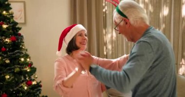 Yaşlı çift Noel ağacının yanında neşeli bir şekilde dans ediyor, şenlikli şapkalar takıyorlar. Son sınıflar, kutlama, tatil, kış, gelenek, aşk