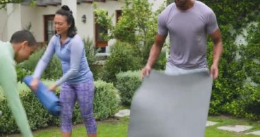 Genç ve çeşitli arkadaşlar yemyeşil bahçe ortamında birlikte egzersiz yapıyorlar. Fitness, egzersiz, arkadaşlık, doğa, sağlık, aktivite