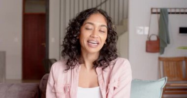 Kıvırcık saçlı, sırıtan bir kadın kanepeye oturmuş video görüşmesinde konuşuyor. Arkadaşlık, rahatlama, mutluluk, rahatlık, sosyalleşme, neşe