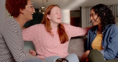 Sohbet ediyor, gülüyor, çeşitli bayan arkadaşlar içeride kanepede eğleniyorlar. Arkadaşlık, kaynaşma, eğlence, mutluluk, oturma odası, rahat