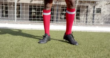 Sahada futbol topunu tekmeliyor, Afro-Amerikan erkek sporcu kırmızı çoraplar ve siyah kramponlar giyiyor. Spor, futbol, yarışma, aksiyon, ayakkabı, üniforma