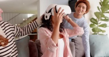 VR kulaklık kullanıyor, kadın arkadaşlarıyla gülüyor, akıllı telefon tutuyor, takılmaktan keyif alıyor. Teknoloji, sosyalleşme, eğlence, eğlence, sanal gerçeklik, kahkaha