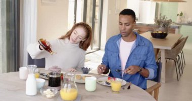 Çeşitli çiftler kahvaltıdan zevk alıyor, birlikte şurup ve kahve dolduruyorlar. Sabah, mutfak, ev hayatı, kaynaşma, birliktelik