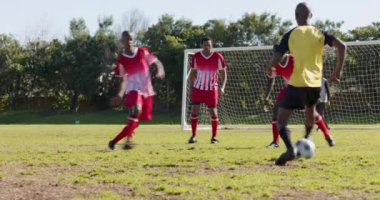 Futbol oynuyor, kırmızı üniformalı erkek oyuncular serbest vuruşa karşı savunma yapıyor. Futbol, savunma, takım çalışması, gol, yarışma, açık hava