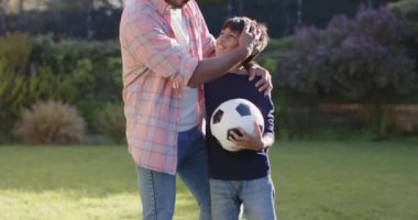 Hintli baba ve oğul futbol topuyla oynuyorlar, dışarıda güzel vakit geçiriyorlar. Aile, kaynaşma, oyun, eğlence, aktivite, ebeveynlik