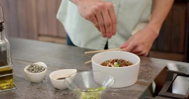 Asyalı bir adam modern mutfakta yemek çubuklarıyla yemek yiyor. Yemek, yemek, yaşam tarzı, ev işleri.