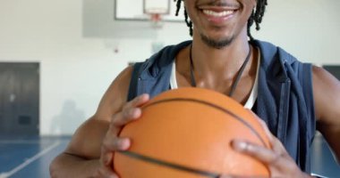 Gülümseyen basketbol koçu spor salonunda topu tutuyor, antrenman için hazır. Spor, takım, antrenman