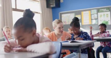 Okulda, bayan öğretmen sınıfta ödev yazmada öğrenciye yardım ediyor. Eğitim, öğrenim, öğretim, danışmanlık, akademik, öğretim