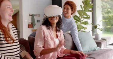 VR kulaklık takan bir kadın, kanepeye oturmuş kız arkadaşlarıyla selfie çekiyor. Teknoloji, sanal gerçeklik, sosyal, eğlenceli, yaşam tarzı