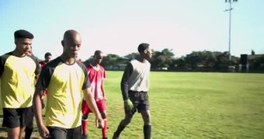 Futbol sahasında yürüyen, formalı erkek futbolcular maça hazırlanıyor. Spor, takım çalışması, fitness, rekabet, hazırlık, sporcular