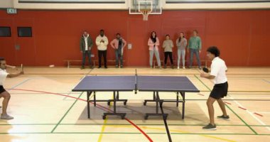 Masa tenisi oynuyorlar, iki adam spor salonunda seyircilerle yarışıyor. Spor, rekabet, sporcular, yoğunluk, maç