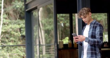 Asyalı adam evde akıllı telefon asistanı kullanıyor, gülümsüyor ve rahatlıyor, kopyalama alanı. Teknoloji, iletişim, aygıt, yaşam tarzı, eğlence, etkileşim