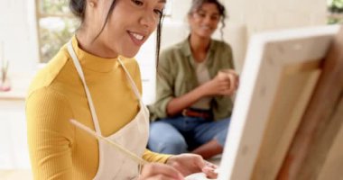 Çok ırklı bayan arkadaşlar evde birlikte resim ve kahve yapmaktan zevk alıyorlar, gülümsüyorlar ve rahatlıyorlar. Arkadaşlar, yaratıcılık, eğlence, sanat, bağ, hobi