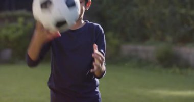 Gülen çocuk dışarıda futbol topu tutuyor, bahçede oyun oynamaktan zevk alıyor. Çocuklar, spor, eğlence, mutluluk, yaz, aktif