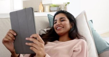 Evde dinlenen, Hintli bir kadın rahat koltukta tabletin tadını çıkarıyor. Teknoloji, eğlence, yaşam tarzı, konfor, dijital, rahatlama