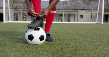 Futbol sahasında ayakkabı bağlama, Afrika kökenli Amerikalı erkek atlet, futbol maçı, fotokopi alanı. Hazırlık, spor, antrenman, rekabet, fitness, Afrikalı Amerikalı erkek oyuncu