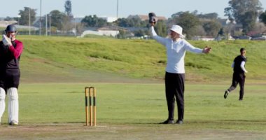 Bowler kriket sahasında hızlı top atıyor, vurucu oyuna hazır. Spor, yarışma, atlet, takım çalışması, saha, oyun