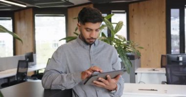 Tablet kullanarak, Hintli adam modern ofiste duruyor, işine odaklanıyor. İş, şirket, teknoloji, işyeri, profesyonel, üretkenlik