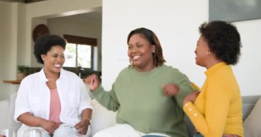 Gülüşmeler, kucaklaşmalar, evdeki kanepede oturan arkadaşlar, birlikte eğlenmeler. Arkadaşlık, yakınlaşma, eğlence, kahkaha, rahatlama, birliktelik.