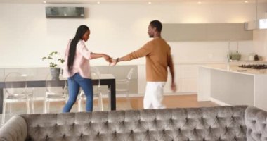 Birlikte dans eden, genç Afro-Amerikan çift evdeki modern mutfakta eğleniyor. Romantizm, aşk, yaşam tarzı, mutluluk, eğlence, birliktelik