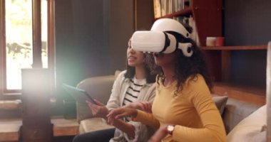 Çok ırklı kadın arkadaşlar evde sanal gerçeklik deneyiminin tadını çıkarıyorlar, gülümsüyorlar ve tablet kullanıyorlar. Teknoloji, eğlence, eğlence, dijital, yaşam tarzı, aygıt