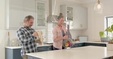 Modern mutfakta paketleri boşaltan olgun bir çift birlikte vakit geçiriyorlar. Aşçılık, yaşam tarzı, mutluluk, ortaklık, ilişki, birliktelik