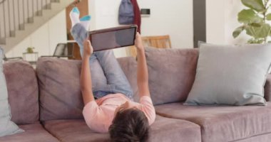 Kanepede dinlenmek, çocuk evde eğlenmek için tablet kullanıyor. Çocukluk, teknoloji, rahatlık, ev, alet, sıradan