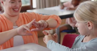 Okulda, kız öğretmen ve öğrenci sınıfta işaret dili çalışırlar. Eğitim, iletişim, öğrenme, öğretim, özel eğitim, eğitmen