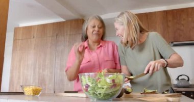 Salata hazırlıyorum, iki tane çok ırklı son sınıf kız arkadaş gülüyor ve evde eğleniyorlar. Yemek, mutfak, arkadaşlık, kahkaha, sağlıklı yaşam tarzı