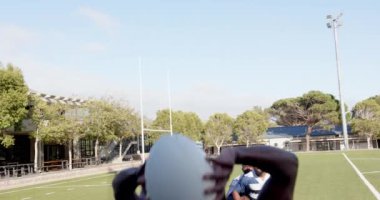 Ragbi oynarken, Afrika kökenli Amerikalı erkekler antrenman sırasında sahada top yakalamak için zıplıyorlar. Spor, takım çalışması, atletik, sahada, rekabet, yakalama