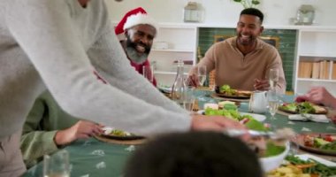 Çeşitli aileler Noel yemeklerini birlikte yiyor, gülüyor ve neşeli anları paylaşıyorlar. tatil, kutlama, yemek, mutluluk, toplanma, birliktelik