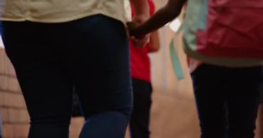 Okul koridorunda yürüyen, sırt çantalı bir grup öğrenciye rehberlik eden bir öğretmen. Eğitim, rehberlik, akıl hocalığı, öğrenme, sınıf, öğretmenler