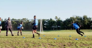 Futbol oynamak, sporcular sahada külahlarla antrenman yapmak ve arka planda gol atmak. Spor, takım çalışması, egzersiz.