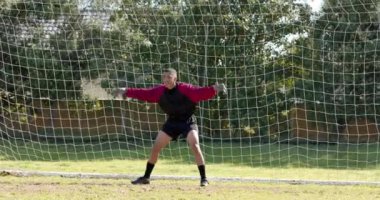 Kaleci güneşli bir günde maç sırasında futbol topunu kurtarmak için dalıyor. Spor, aksiyon, rekabet, futbol, dalış, atlet