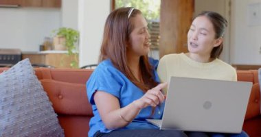 Kanepede oturmak, Asyalı anne-kız dizüstü bilgisayar kullanmak, birlikte güzel vakit geçirmek. Aile, bağ, teknoloji, ev, boş zaman, birliktelik.