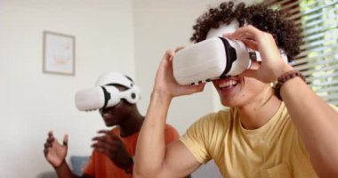 VR kulaklıklar takan iki çok ırklı erkek arkadaş evde sanal gerçeklik deneyiminin tadını çıkarıyor. teknoloji, eğlence, oyun, çok ırklı erkek arkadaşlar, eğlence, fütüristik
