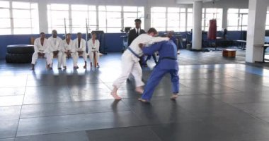 Judo antrenmanı yapıyorlar, sporcular paspasın üzerinde antrenman yaparken diğerleri dojo 'da izliyor. Dövüş sanatları, eğitim, spor, dövüş, rekabet, takım çalışması