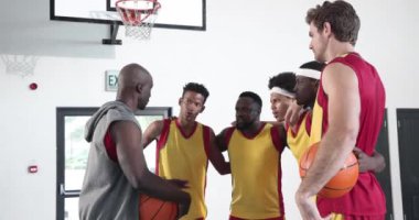Basketbol takımı zaferi kapalı sahada beşlik çakarak kutluyor. Takım çalışması, başarı, sportmenlik, rekabet, birlik, kutlama