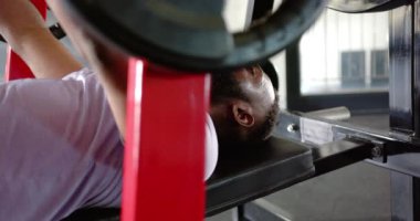 Ağırlık kaldıran ağırlık kaldıran, spor salonundaki dayanıklılık eğitimine odaklanan Afrikalı Amerikalı bir adam. Spor, vücut geliştirme, egzersiz, Afrika kökenli Amerikalı erkek sporcu, kas gücü.