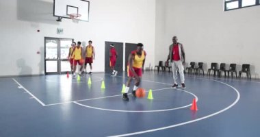 Basketbolcular spor salonunda antrenman yaparken koç gözlemliyor. Spor, antrenman, antrenman, takım çalışması, atlet, spor salonu