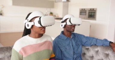 VR kulaklıkları takan genç Afro-Amerikan çift evde sanal gerçeklik deneyiminin tadını çıkarıyor. teknoloji, eğlence, eğlence, fütüristik, kapalı alan, oyun