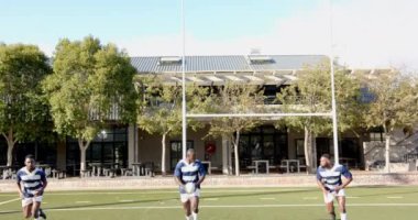 Sahada ragbi oynayan, spor üniformalı Afro-Amerikan erkekler takım çalışması yapıyor. antrenman, yarışma, sporcular, fitness, sahada