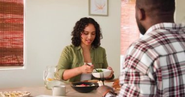 Gülümseyen, çok kültürlü bir çift pazar yemeklerini evde yiyor, yemeklerini paylaşıyorlar. akşam yemeği, aile, kutlama, bayram, ziyafet, birliktelik