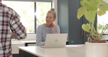 Evde dizüstü bilgisayarla kahve içip sohbet eden olgun bir çift. Yaşam tarzı, teknoloji, rahatlama, evcil, birliktelik, rahatlık