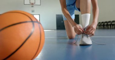 Ayakkabı bağcıkları bağlamak, basketbol oyuncusunun kapalı sahada maça hazırlanması. Spor, atlet, hazırlık, ayakkabı, antrenman, yarışma