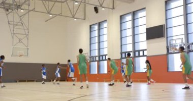 Basketbol oynuyorlar, takım üyeleri oyun sırasında kapalı sahada oynuyorlar. Spor, takım çalışması, yarışma, kapalı alan, sporcular, dinamik