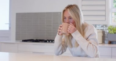 Gülümseyen kadın evde kahveyle eğleniyor, rahat bir mutfakta rahatlıyor, fotokopi çekiyor. Rahatlama, yaşam tarzı, içecek, sabah, rahatlık, aile içi