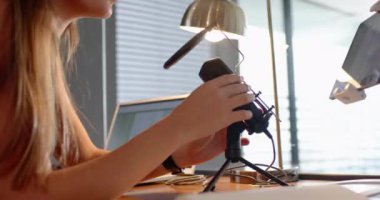Ses kaydı, ev çalışma alanında mikrofon ve laptop kullanan bir kadın. Podcasting, teknoloji, ev ofisi, uzaktan çalışma, profesyonel, yaratıcılık