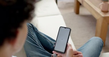 Akıllı telefonu tutan, kanepede oturan ve evdeki mobil uygulamayı kullanan genç bir çocuk. Teknoloji, modern, boş zaman, internet, iletişim, kapalı alan